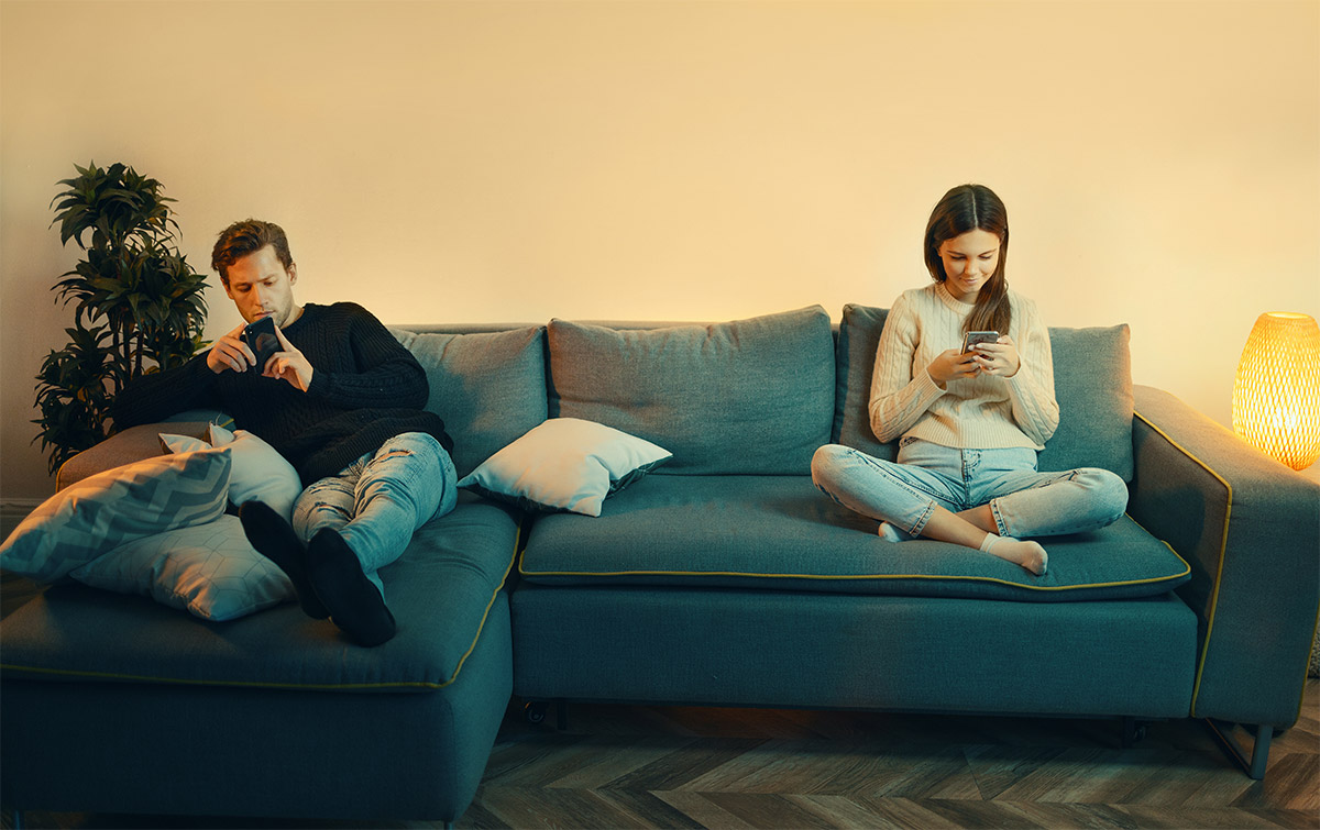 Couple On Couch Ignoring Each Other On Phones